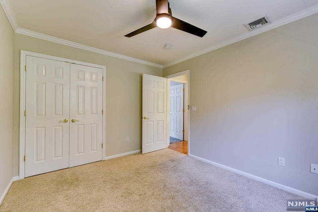 unfurnished bedroom with light carpet, a closet, ceiling fan, and crown molding