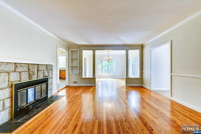 unfurnished living room featuring hardwood / wood-style flooring, ornamental molding, a fireplace, and a chandelier