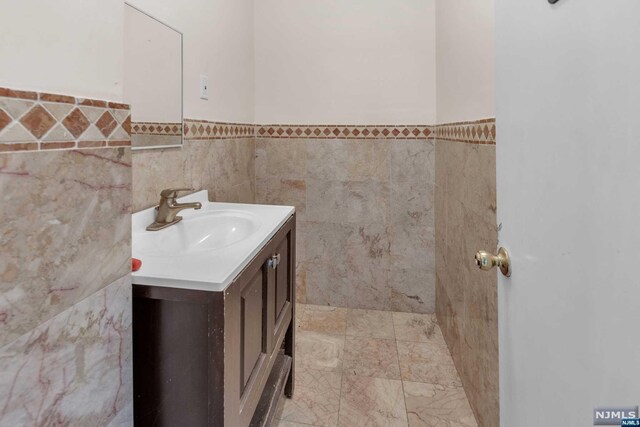 bathroom featuring vanity and tile walls