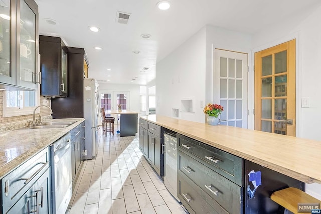 kitchen with french doors, sink, appliances with stainless steel finishes, tasteful backsplash, and light stone counters