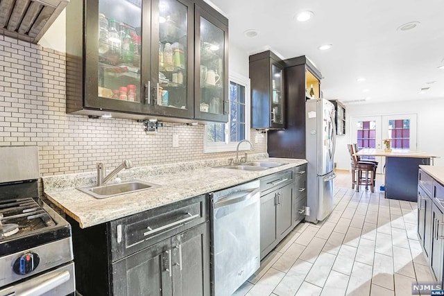 kitchen with light stone countertops, sink, light tile patterned floors, and appliances with stainless steel finishes