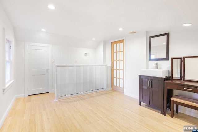 interior space featuring sink, lofted ceiling, and light hardwood / wood-style flooring