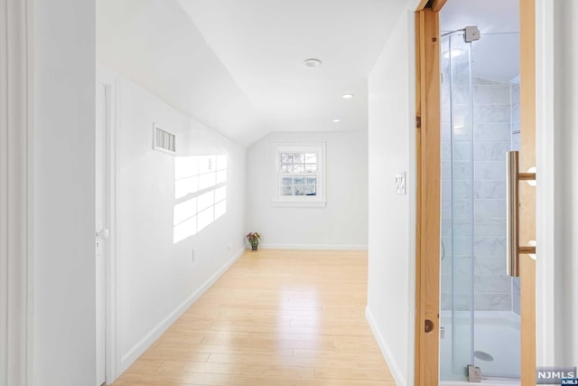 interior space with lofted ceiling, hardwood / wood-style flooring, and a shower with shower door