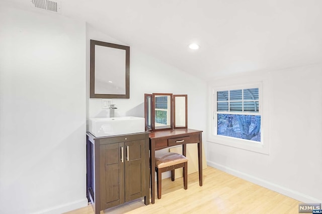 bathroom featuring vanity, vaulted ceiling, and hardwood / wood-style flooring