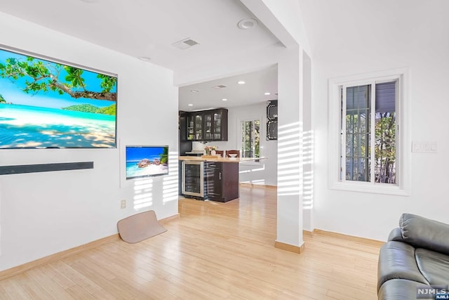 living room with wood-type flooring, indoor bar, beverage cooler, and a healthy amount of sunlight