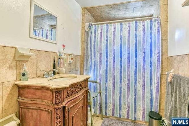 bathroom featuring vanity and tile walls