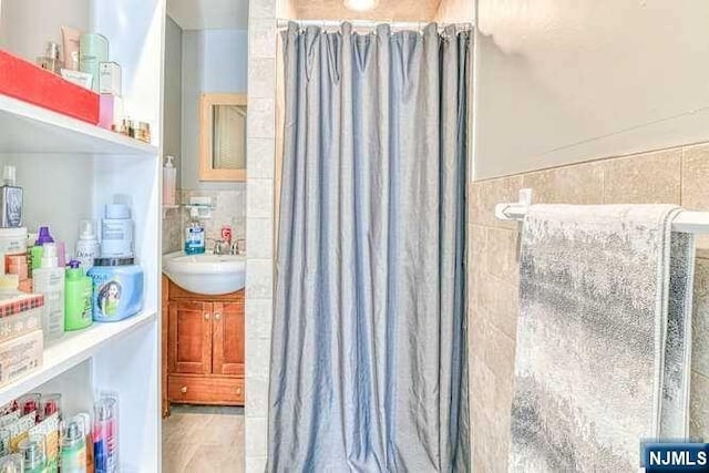 bathroom with a shower with curtain, vanity, and tile walls