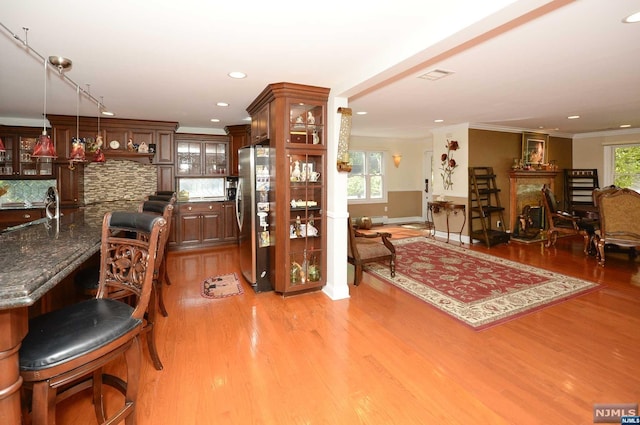 interior space with light wood-type flooring, crown molding, and sink