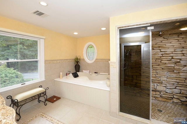 bathroom with tile patterned flooring, plus walk in shower, and tile walls