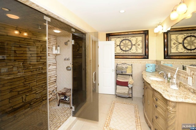 bathroom featuring tile patterned floors, a shower, vanity, and tile walls