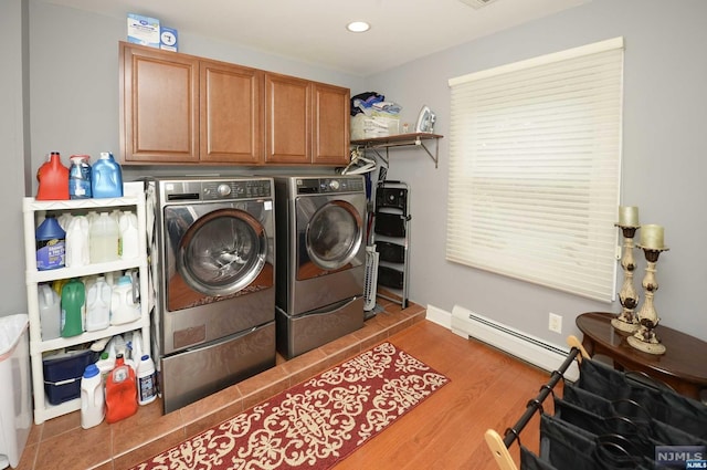 clothes washing area with separate washer and dryer, hardwood / wood-style floors, a baseboard radiator, and cabinets