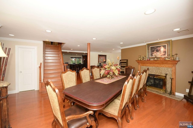 dining room with a fireplace, hardwood / wood-style flooring, and crown molding