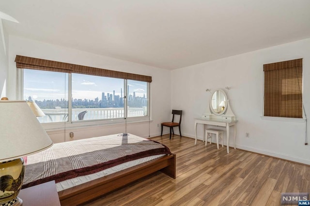 bedroom with light hardwood / wood-style floors and a water view