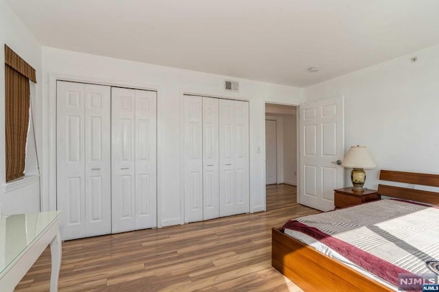 bedroom featuring hardwood / wood-style floors and multiple closets