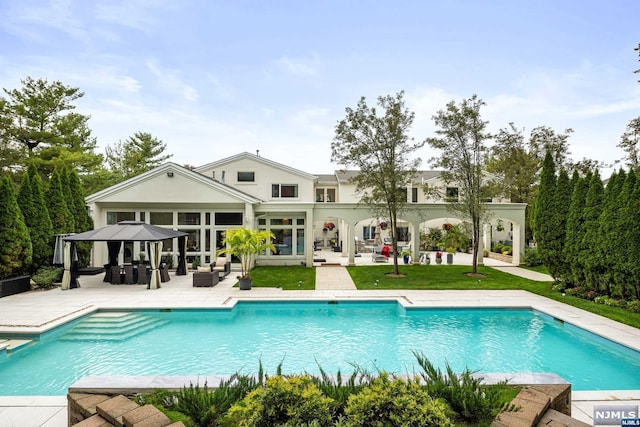 back of property featuring a gazebo, a patio area, a yard, and an outdoor hangout area