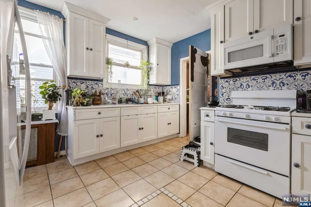 kitchen with decorative backsplash, white cabinetry, and white appliances