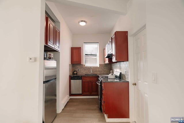 kitchen featuring appliances with stainless steel finishes, backsplash, sink, a baseboard radiator, and light hardwood / wood-style floors