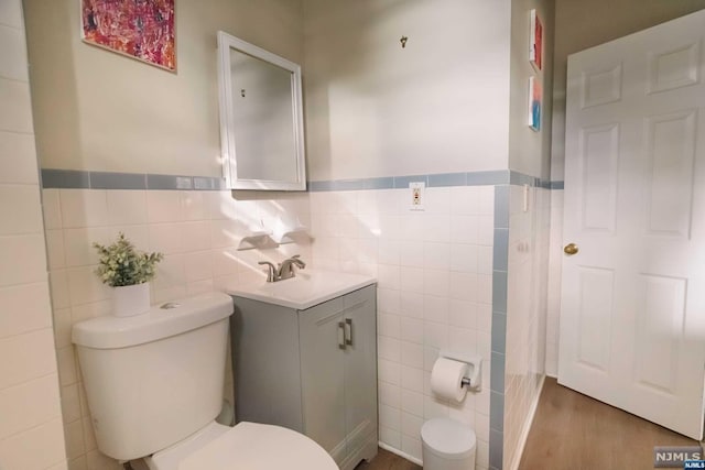 bathroom with hardwood / wood-style flooring, vanity, tile walls, and toilet