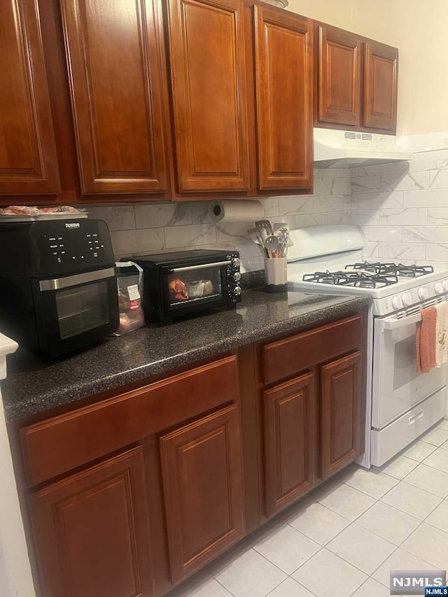 kitchen featuring tasteful backsplash, gas range gas stove, and light tile patterned flooring