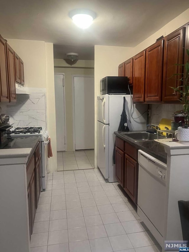 kitchen featuring gas stove, tasteful backsplash, white dishwasher, and light tile patterned floors