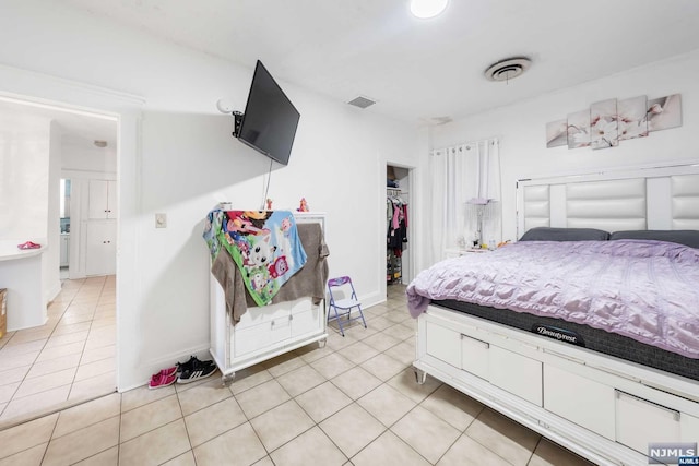 tiled bedroom featuring a walk in closet and a closet