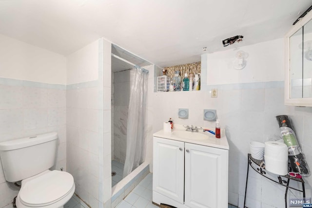 bathroom with walk in shower, tile patterned floors, toilet, vanity, and tile walls