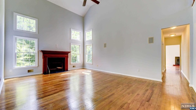 unfurnished living room featuring plenty of natural light, high vaulted ceiling, and light hardwood / wood-style floors