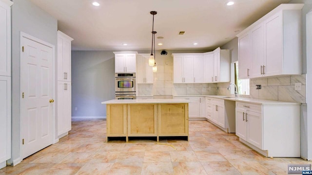 kitchen featuring a center island, white cabinetry, hanging light fixtures, and double oven