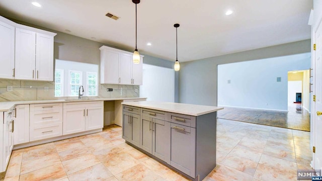 kitchen featuring pendant lighting, gray cabinetry, white cabinetry, and sink