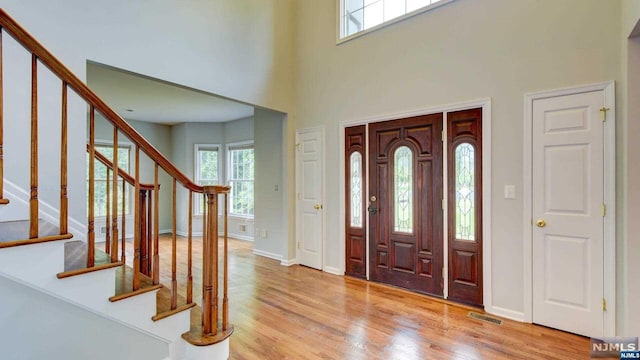 entryway with light hardwood / wood-style flooring and a towering ceiling