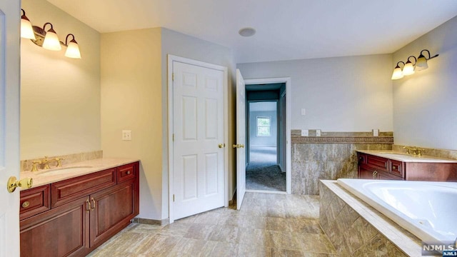 bathroom with vanity and tiled tub