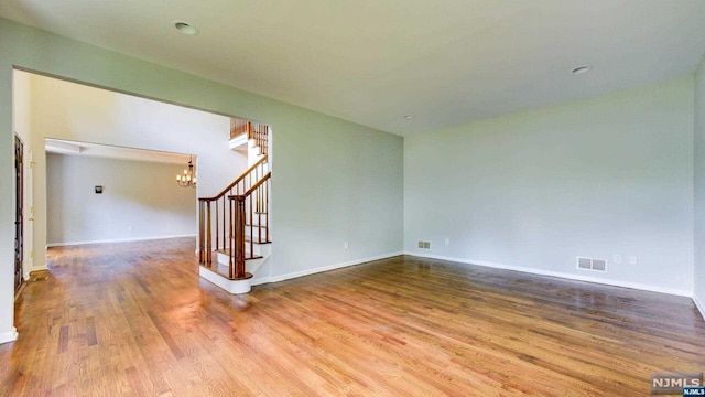 unfurnished room featuring hardwood / wood-style floors and a notable chandelier