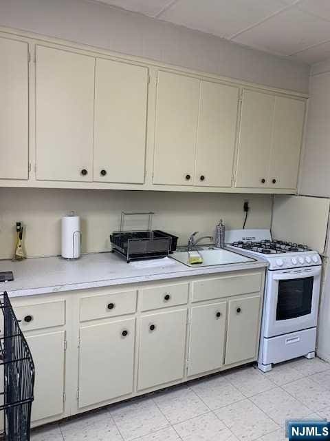 kitchen with white cabinets, sink, and white range with gas cooktop