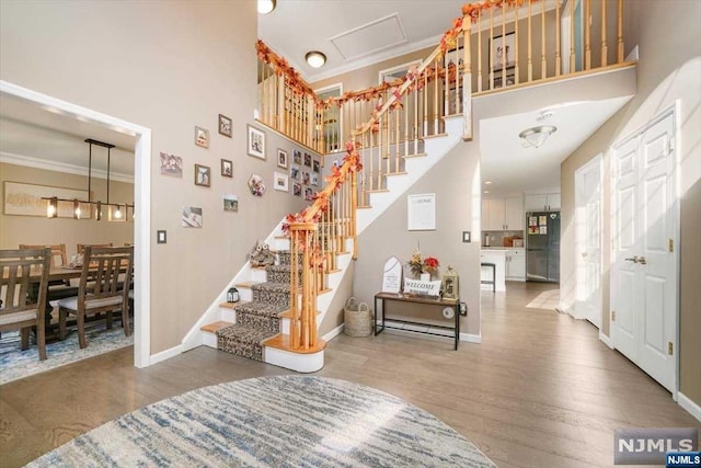 stairs with crown molding, a high ceiling, and hardwood / wood-style flooring