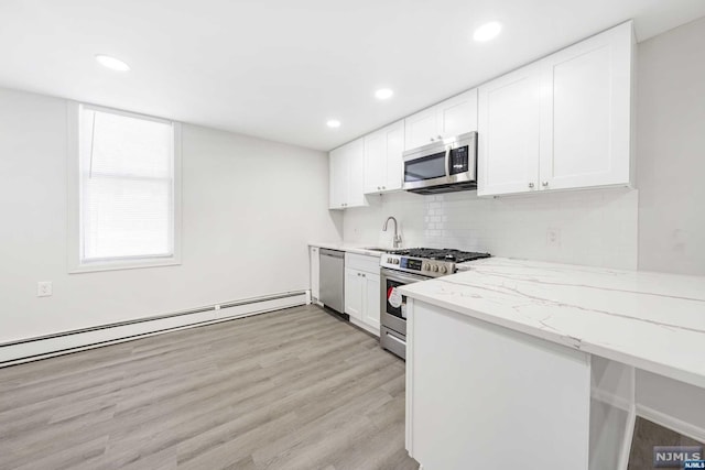 kitchen with light wood-type flooring, stainless steel appliances, white cabinetry, and a baseboard radiator