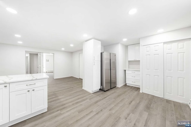 basement featuring light hardwood / wood-style floors and stainless steel refrigerator