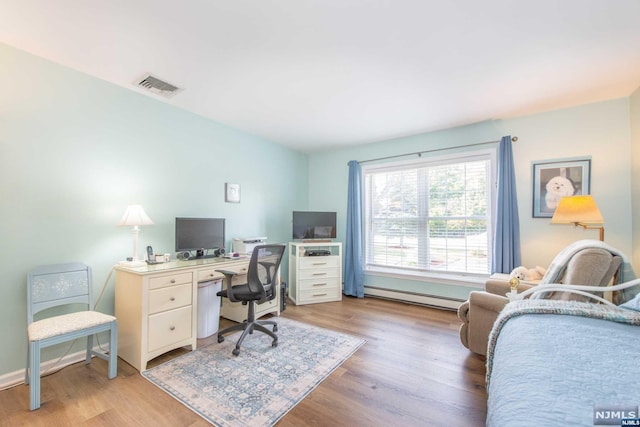 office with light hardwood / wood-style floors and a baseboard heating unit