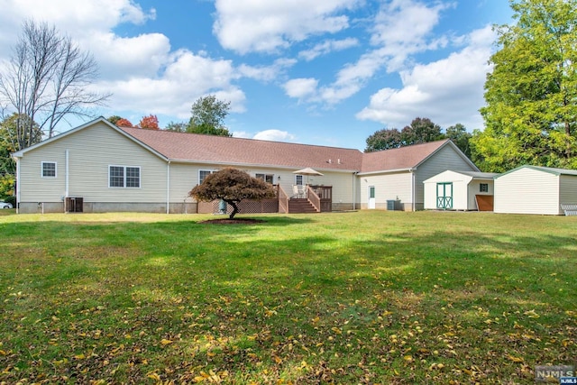 rear view of property with a yard, cooling unit, and a storage shed