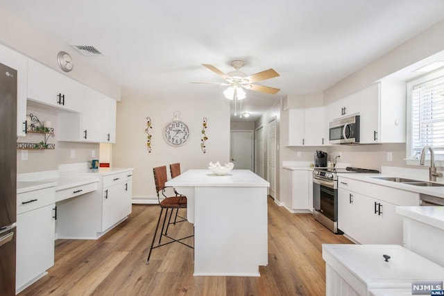 kitchen featuring appliances with stainless steel finishes, light wood-type flooring, white cabinetry, and sink