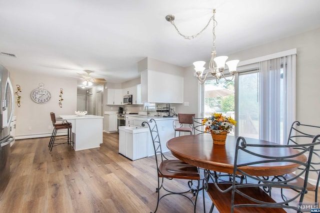 dining room with ceiling fan with notable chandelier, light hardwood / wood-style flooring, and sink