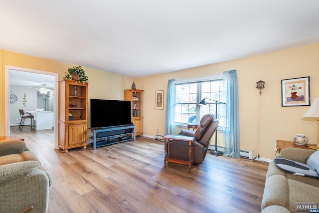 living room with baseboard heating, ceiling fan, and light hardwood / wood-style flooring