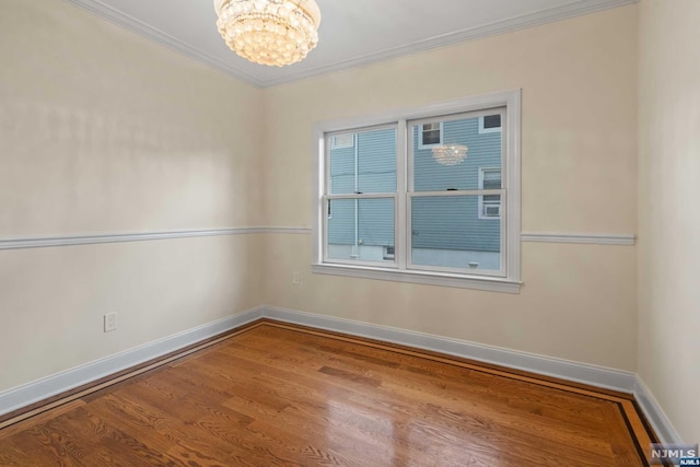 spare room with hardwood / wood-style floors, a notable chandelier, and ornamental molding