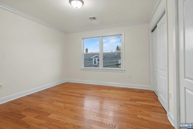 unfurnished bedroom with light wood-type flooring, a closet, and crown molding