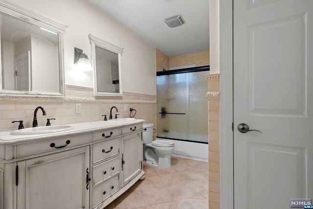 full bathroom featuring shower / bath combination with glass door, tile patterned flooring, vanity, and toilet