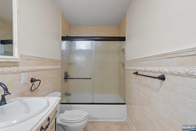 full bathroom featuring vanity, tile walls, enclosed tub / shower combo, tile patterned flooring, and toilet