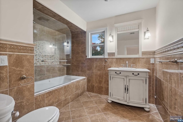 full bathroom featuring vanity, tiled shower / bath combo, tile walls, tile patterned flooring, and toilet