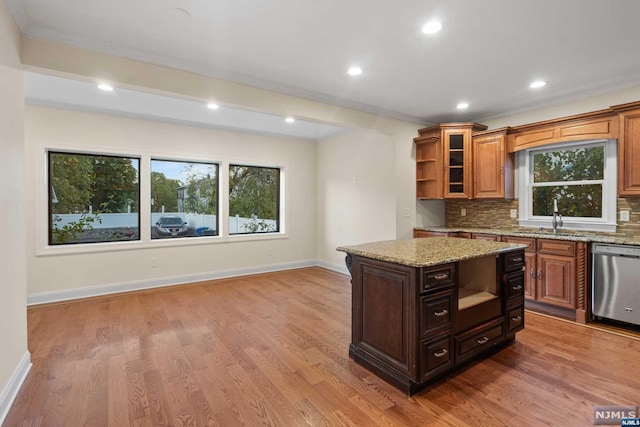 kitchen with stainless steel dishwasher, sink, light stone counters, and hardwood / wood-style floors