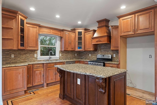 kitchen featuring light stone countertops, sink, stainless steel gas range, light hardwood / wood-style flooring, and custom range hood