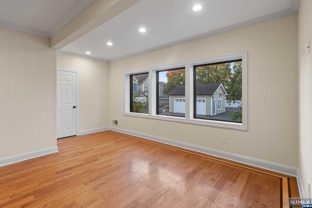 spare room with ornamental molding and light hardwood / wood-style flooring