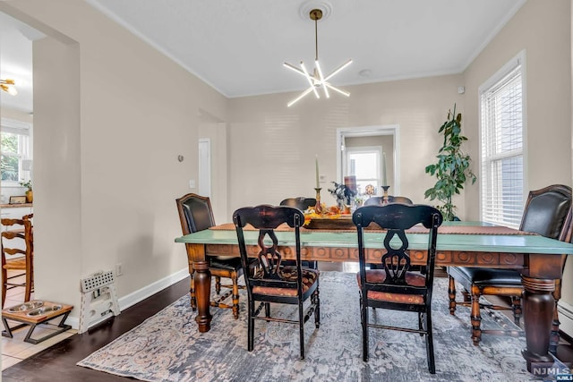 dining area with a healthy amount of sunlight, wood-type flooring, crown molding, and an inviting chandelier